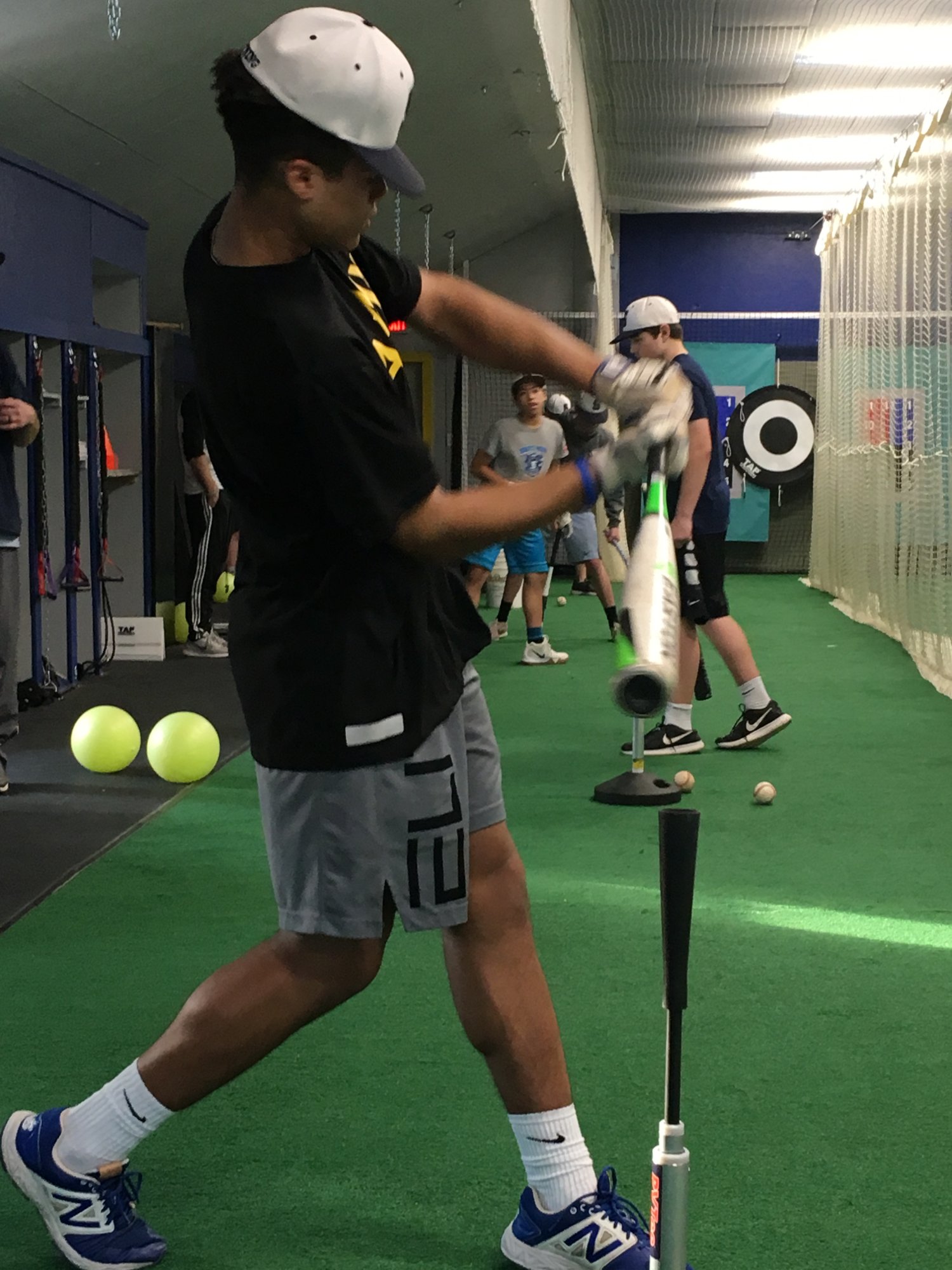 A young hitter driving through his swing in the cage