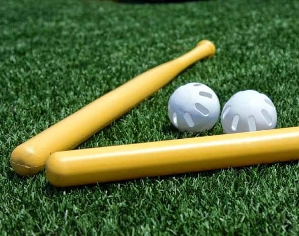 Two yellow Wiffle bats and Wiffle balls on the turf